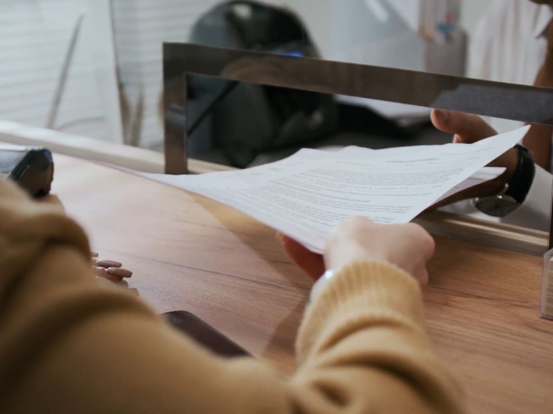 osoba predaje papire osobi na salteru