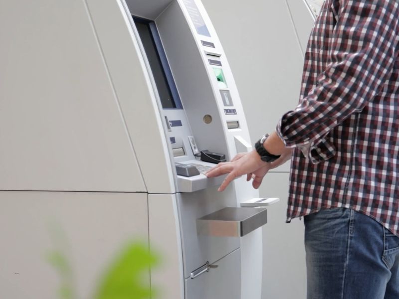 osoba podiže novac sa bankomata