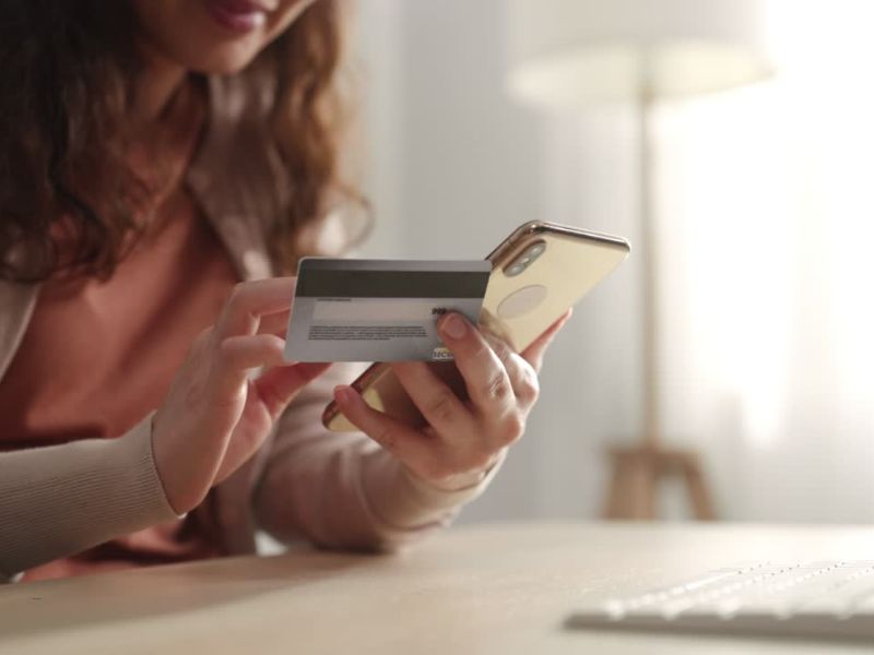 devojka drži telefon i kreditnu karticu u ruci