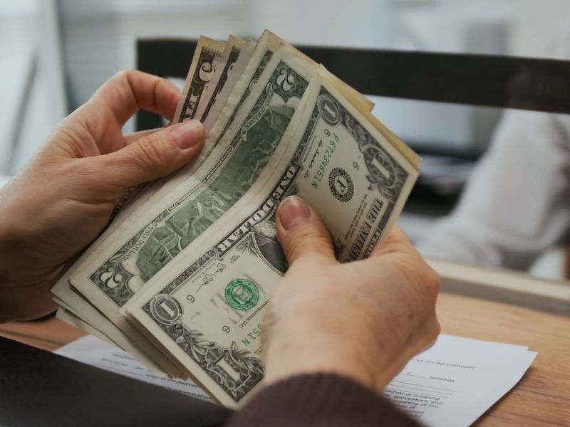 osoba broji novac na šalteru u banci